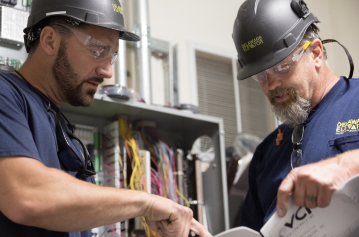 two men in hard hats looking at a piece of paper