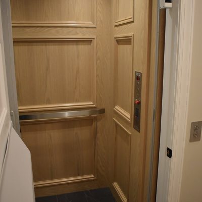 B2B elevator with wooden walls and a grab handle