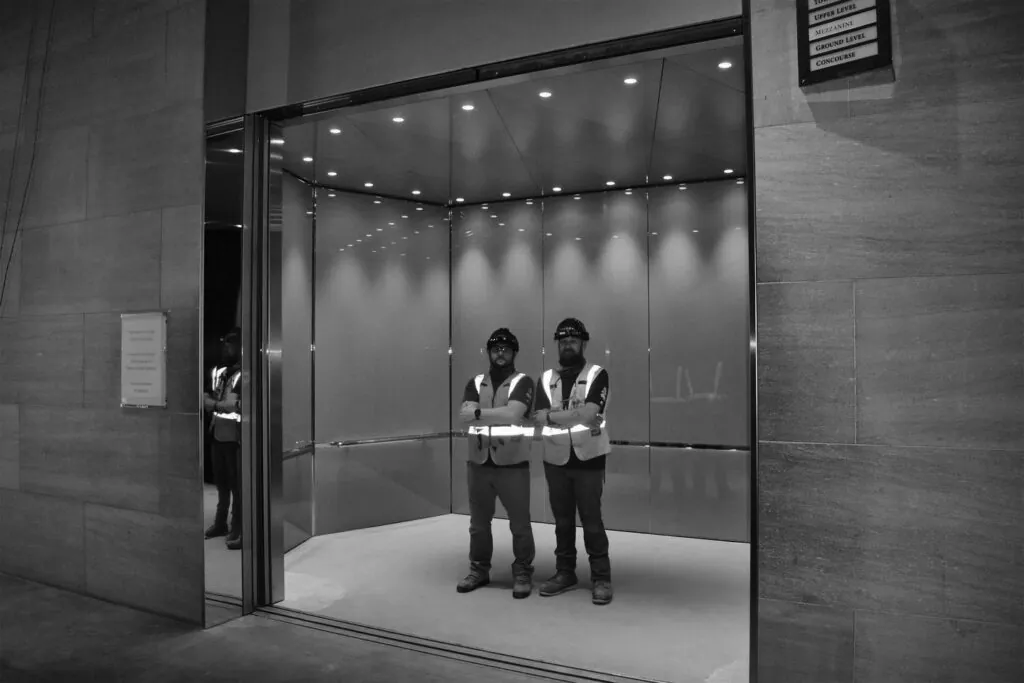 a couple of men standing in front of a glass wall